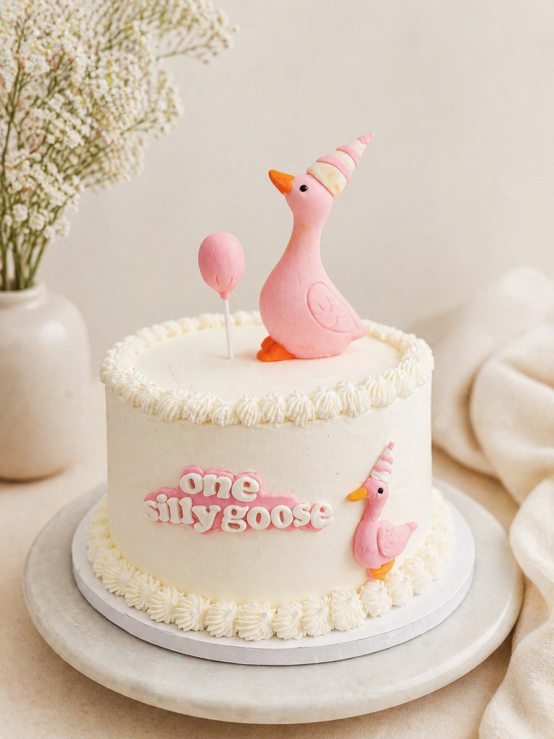 First-birthday cake decorated with handcrafted pink goose figures