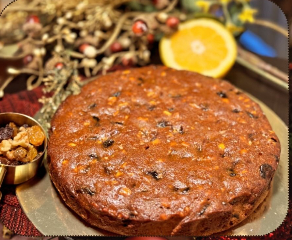 Round Christmas fruit cake with dried fruits and nuts, styled with orange and holiday greenery