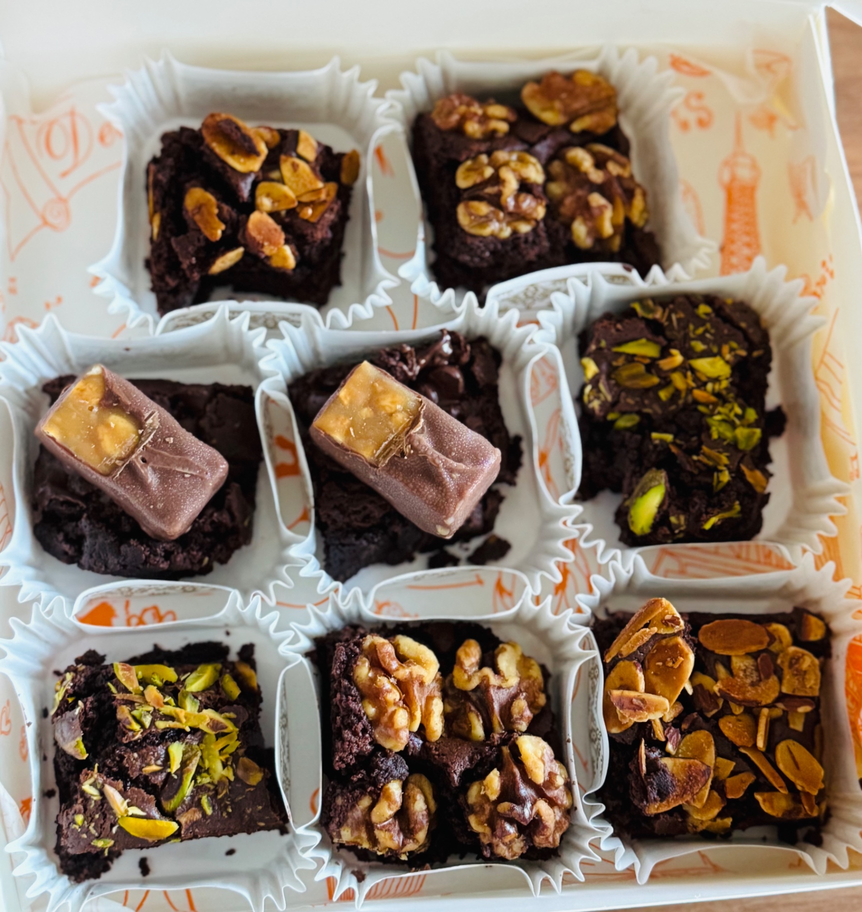 Gift box of assorted brownies topped with walnuts, pistachios and caramel chocolate